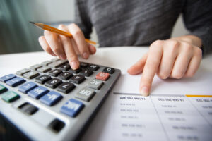 Dicas para renegociar dívidas pessoa calculando com papel em cima da mesa 