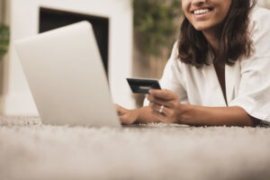 mulher segurando cartão de crédito e realizando compra na internet 